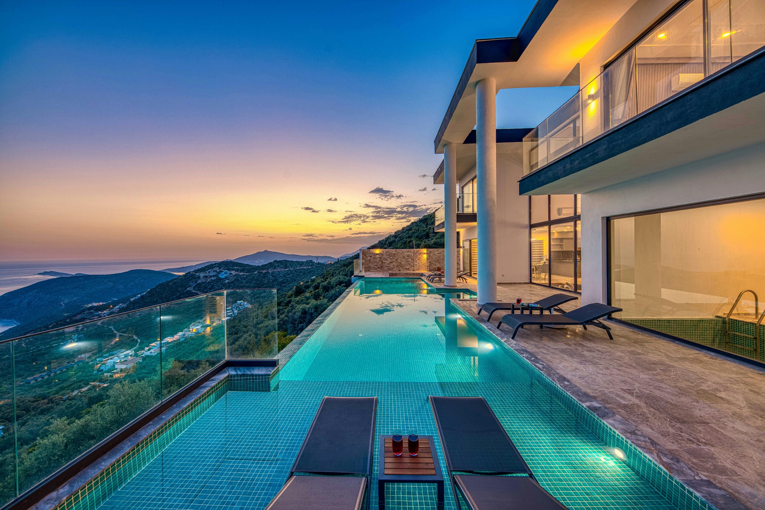 Stunning luxury villa overlooking the ocean with an infinity pool at sunset.